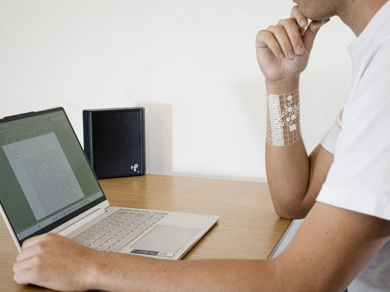 a person sitting at a computer with a device on their arm