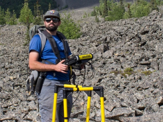 man standing on rocky terrain with electrical equipment