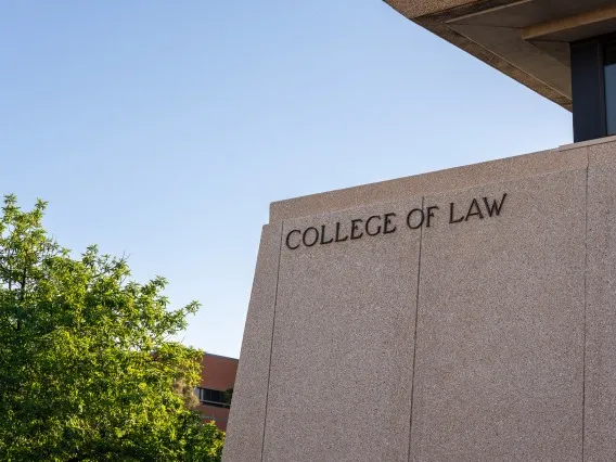 lettering on the college of law building that reads "college of law" with trees in the background