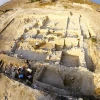 an overhead view of a stone foundation in the ground where archaeologists are excavating ancient remains